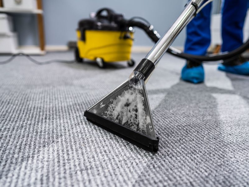 Person Cleaning Carpet With Vacuum Cleaner