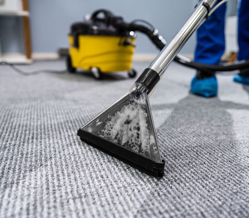 Person Cleaning Carpet With Vacuum Cleaner