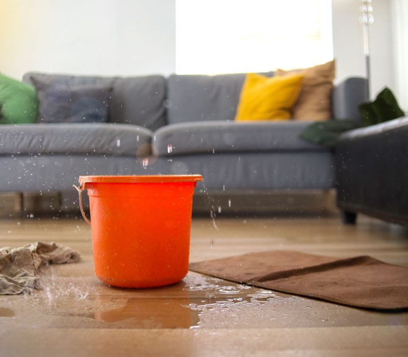water-dripping-from-ceiling-into-bucket-floor-living-room-leaking-roof-concept