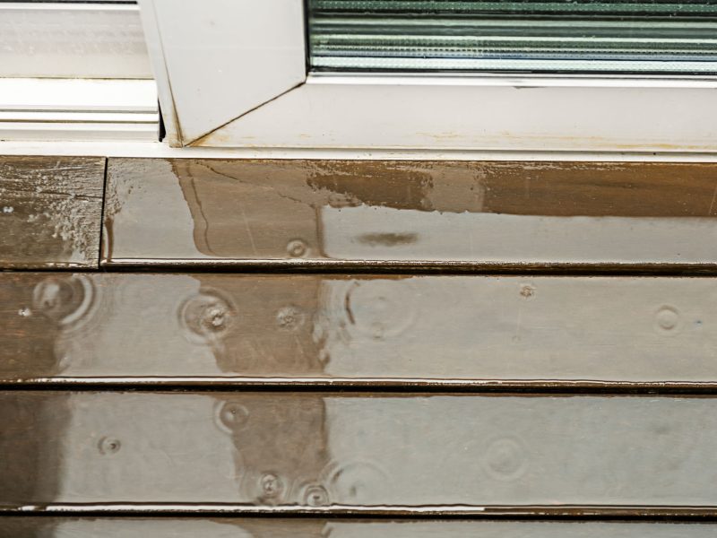 Wooden plank floor of a terrace filled with rainwater and with the waves produced by the water drops.